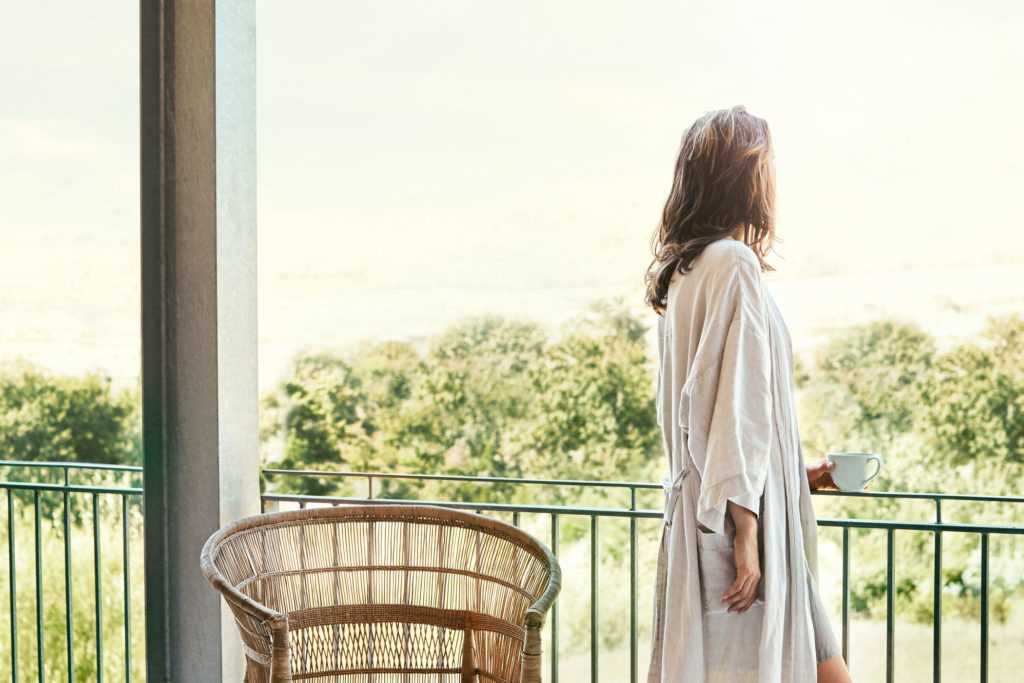 A woman in a robe looking over her balcony to view the scenery