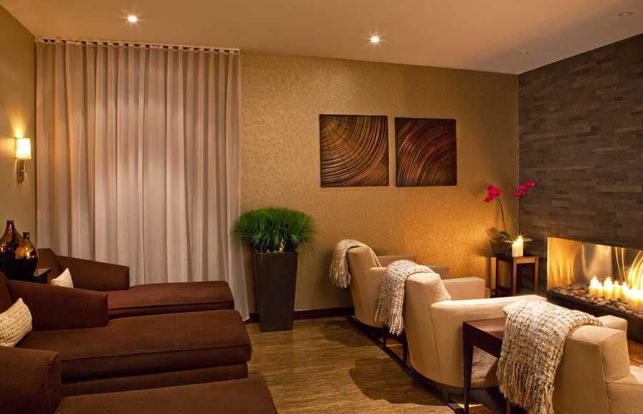 the spa relax room with lounge chairs and three armchairs in front of a fireplace