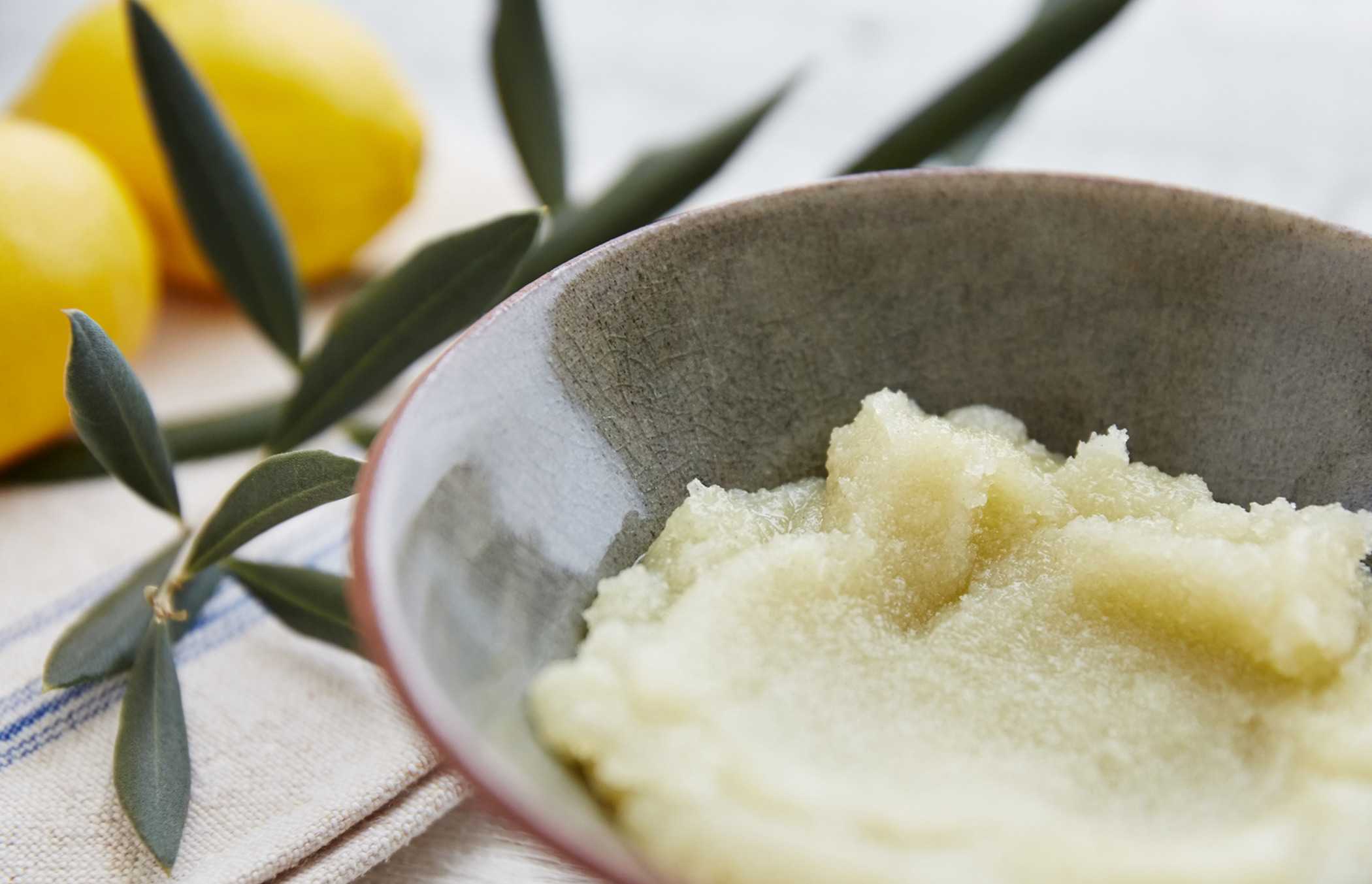 A bowl of body scrub neatly placed aside lemons