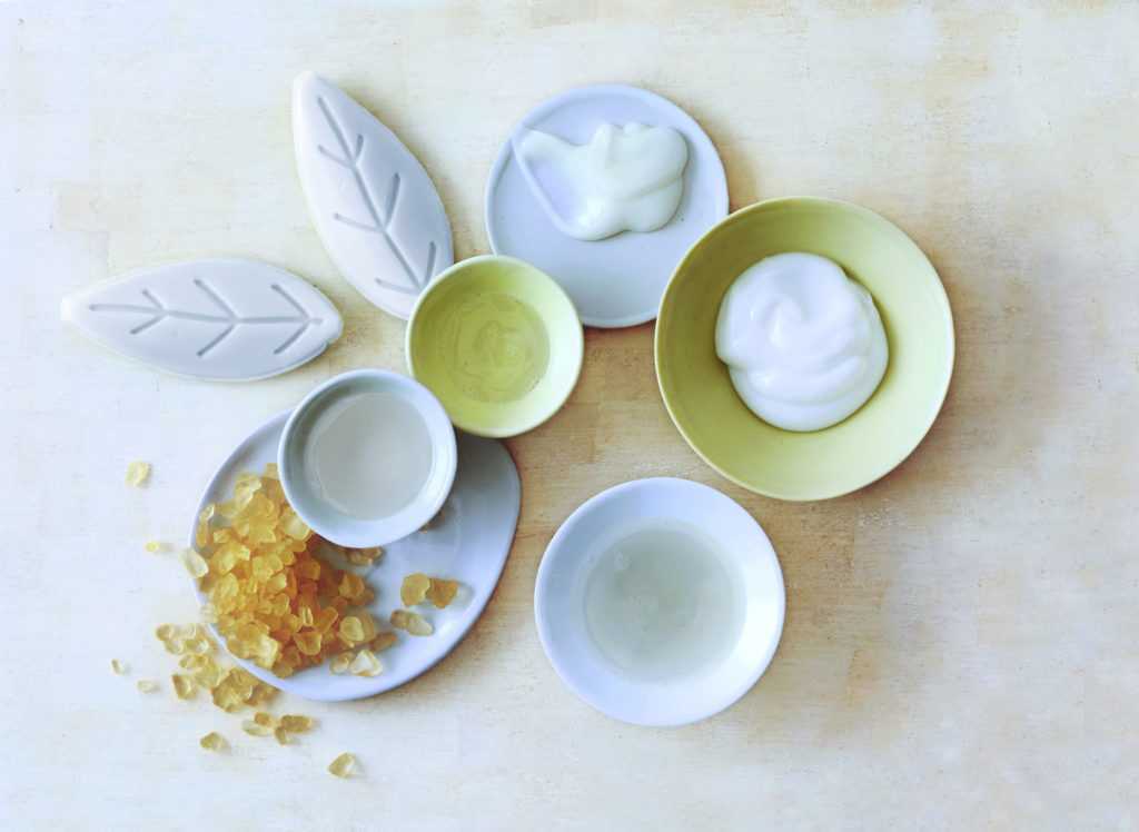 An arrangement of various bowls and plates holding spa scrubs and creams