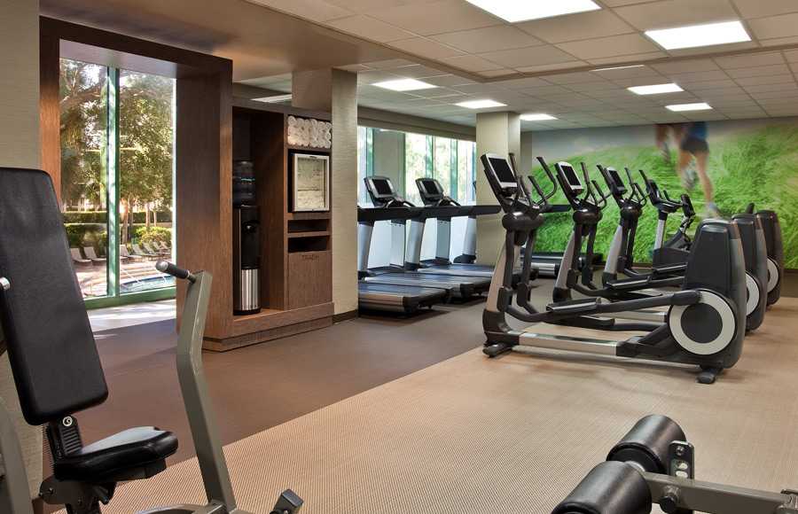 A fitness room full of gym equipment and large windows