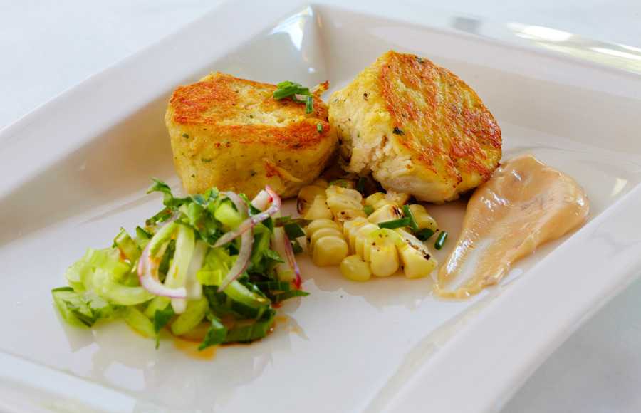 A delicious food shot of two crab cakes neatly placed on a crisp white plate