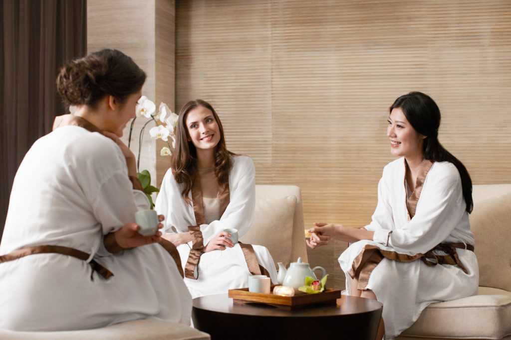 a group of three girls gathered around a table in their robes at a spa