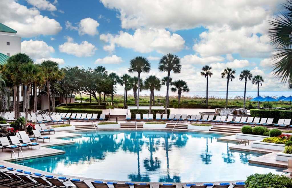 A pool with lounge chairs and palm trees surrounding the pool deck
