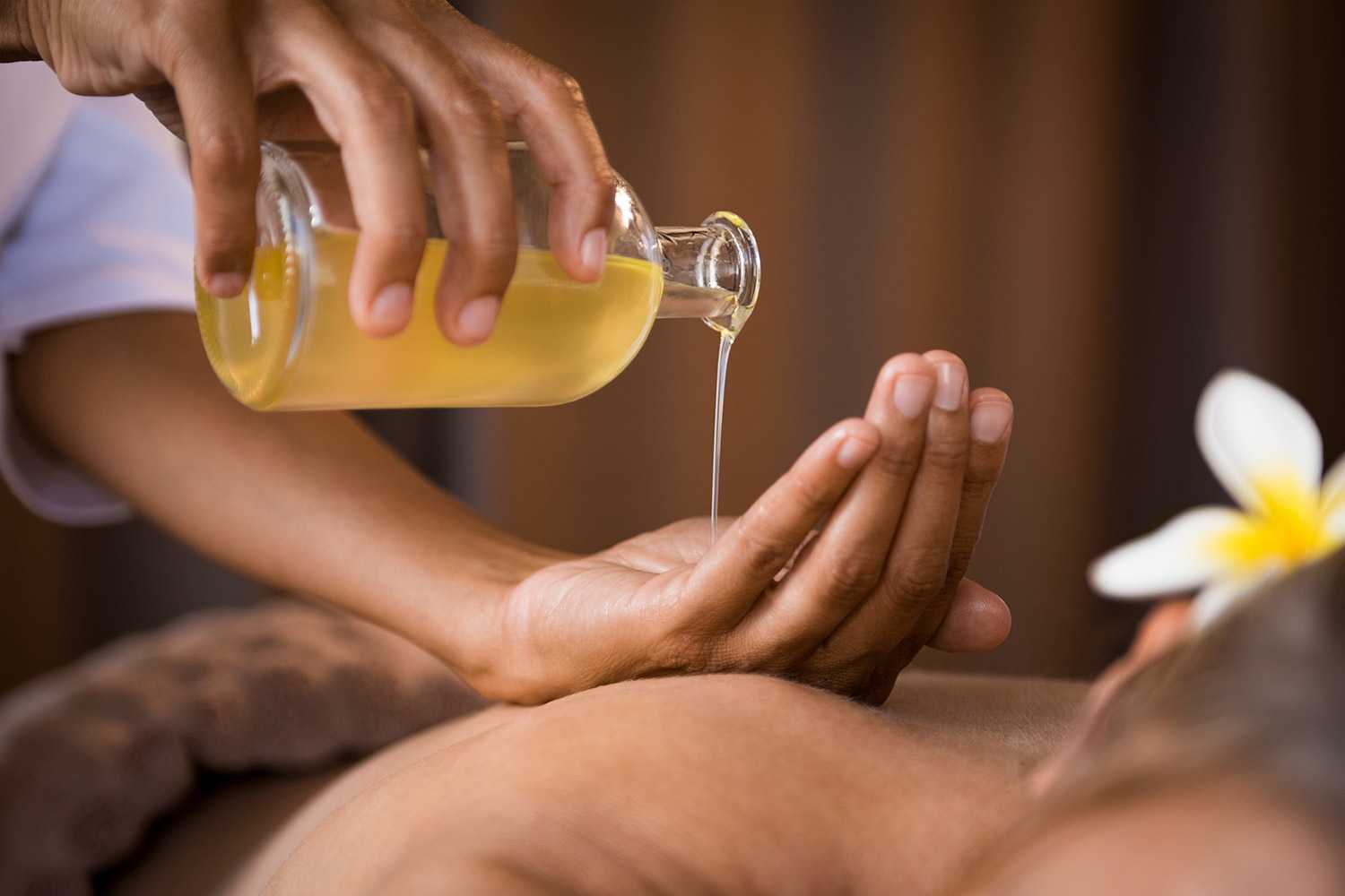 person pouring oil on to someone's back